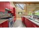 Bright kitchen featuring custom red cabinets, stainless steel appliances, tiled backsplash and expansive skylight at 343 Lakewood Pointe Dr, Roxboro, NC 27574