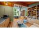 Open-concept living room with hardwood floors, wooden beamed ceilings and large windows with views of the trees at 343 Lakewood Pointe Dr, Roxboro, NC 27574