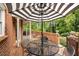 Brick patio with brick retaining wall, black iron table, chairs, and umbrella at 441 Fieldstone Dr, Burlington, NC 27215