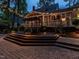 Expansive multi-level deck featuring inviting dining area and screened-in porch, surrounded by lush greenery and ambient lighting at 4716 Shadow Ridge Ct, Holly Springs, NC 27540