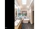 A bathroom featuring a soaking tub under a skylight and a wooden vanity with modern fixtures at 4716 Shadow Ridge Ct, Holly Springs, NC 27540