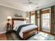 A bedroom featuring a large bed, hardwood floors, neutral-colored walls, two windows, and modern decor at 4716 Shadow Ridge Ct, Holly Springs, NC 27540