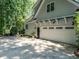 Spacious three car garage showcases carriage doors, accent lighting and manicured greenery at 4716 Shadow Ridge Ct, Holly Springs, NC 27540