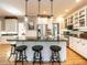An open, eat-in kitchen with a bar, stainless steel refrigerator and appliances, custom cabinets, and hardwood floors at 4716 Shadow Ridge Ct, Holly Springs, NC 27540