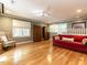 Large living room with hardwood floors, red sofa, and ample natural light at 4716 Shadow Ridge Ct, Holly Springs, NC 27540