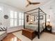 A bedroom featuring a four-poster bed, ceiling fan, hardwood floors, and a window with plantation shutters at 4716 Shadow Ridge Ct, Holly Springs, NC 27540