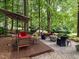 Cozy backyard features deck, stone patio, fire pit, and comfortable seating amidst lush greenery at 4716 Shadow Ridge Ct, Holly Springs, NC 27540