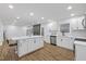 Open-concept kitchen features a center island, stainless appliances, and modern white cabinetry at 5110 Old Well St, Durham, NC 27704
