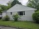 Side view of a newly renovated home with light grey paint, white trim, and green shrubbery at 605 E Montgomery St, Henderson, NC 27536