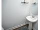 Powder room featuring a pedestal sink, round mirror, and a neutral color palette at 609 Ramsours Mill Dr, Holly Springs, NC 27540