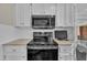 A modern kitchen stove sits below a built-in microwave with white cabinets surrounding it at 7601 Wellesley N Park, Raleigh, NC 27615