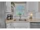A kitchen sink is surrounded by white cabinets, granite countertops, and a window at 7601 Wellesley N Park, Raleigh, NC 27615