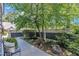 A peaceful side yard with a decorative fence, lush plants, and a seating area with chair at 7601 Wellesley N Park, Raleigh, NC 27615