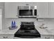 Modern kitchen equipped with stainless steel microwave and electric range, complemented by sleek white cabinets and marble countertops at 821 Onslow St, Durham, NC 27705