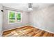 Bright bedroom with laminate floors, neutral-colored walls, and a window with wooded views at 8620 Glendale Dr, Apex, NC 27539