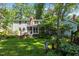 Serene backyard featuring a lush lawn, mature trees, and screened porch at 924 Pebblebrook Dr, Raleigh, NC 27609