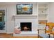 Cozy fireplace featuring a brick surround, mantle with decor, and built-in shelving at 924 Pebblebrook Dr, Raleigh, NC 27609