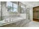 Modern bathroom showcasing a soaking tub with marble tile surround and a separate glass-enclosed shower at 9513 Wood River Dr, Zebulon, NC 27597