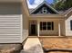 Inviting covered front porch with classic columns, a brick foundation and traditional entry door at 987 Lewis Rd, Zebulon, NC 27597