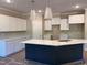 Modern kitchen featuring white cabinets, an island with navy blue accents, and elegant pendant lighting at 987 Lewis Rd, Zebulon, NC 27597