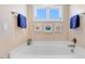 Bright bathroom featuring a soaking tub, blue accents and decorative wall art at 104 Bollienger Dr, Princeton, NC 27569