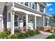 Charming front porch featuring gray rocking chairs, hanging flower baskets, and a quaint blue door at 104 Bollienger Dr, Princeton, NC 27569