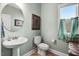 Cozy powder room features a pedestal sink, oval mirror, framed art, and a window with soft curtains at 104 Bollienger Dr, Princeton, NC 27569
