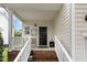 Covered front porch with brick steps, white railings, decorative chair, and black front door with sidelight at 109 Troyer Pl, Apex, NC 27502