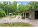 Large backyard with a patio area, stone fire pit, and a charming shed surrounded by beautiful trees at 1115 Sepelo Way, Efland, NC 27243