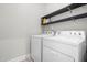 Functional laundry room featuring a washer, dryer, and overhead shelving for storage and organization at 115 Jensen Dr, Wendell, NC 27591