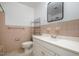 Retro bathroom features pink tiling, white vanity, toilet, silver shelves and silver towel racks at 134 Chateau Rd, Durham, NC 27704