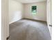 This bedroom features neutral carpeting, a window providing natural light, and closet for storage at 1413 Chamblee Rd, Zebulon, NC 27597
