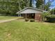 Charming brick home with a covered porch, surrounded by a lush green lawn and mature trees at 1413 Chamblee Rd, Zebulon, NC 27597