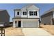 Charming two-story home featuring a two-car garage, sleek black accents, and a 'For Sale' sign in the window at 144 Bruce Dr, Dunn, NC 28334