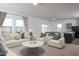 Bright living room featuring large windows, neutral-toned furniture, and an open concept layout to kitchen and dining area at 153 Gladstone Loop, Clayton, NC 27520