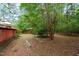 This expansive backyard offers a peaceful setting, bordered by mature trees and a charming wooden deck at 174 Woodwedge Way, Sanford, NC 27332