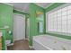 Green-walled bathroom with a white tub, glass block window, and enclosed shower at 174 Woodwedge Way, Sanford, NC 27332