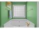 Green bathroom featuring a tub with gold-toned hardware and a unique glass block window at 174 Woodwedge Way, Sanford, NC 27332