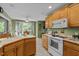 Cozy kitchen with wood cabinetry, white appliances, and adjacent dining area with natural light at 174 Woodwedge Way, Sanford, NC 27332