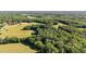 Extensive aerial view highlighting the property's placement among surrounding trees and open fields for a country atmosphere at 1973 Elon Ossipee Rd, Elon, NC 27244