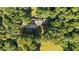 An aerial view of the property, revealing a well-maintained roof, mature trees and an outbuilding with a drive at 1973 Elon Ossipee Rd, Elon, NC 27244