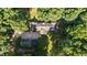 An aerial view of the property, revealing a well-maintained roof, mature trees and an outbuilding with a drive at 1973 Elon Ossipee Rd, Elon, NC 27244