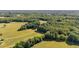 Overhead view showcases a home encircled by mature trees and open fields, offering privacy and natural beauty at 1973 Elon Ossipee Rd, Elon, NC 27244