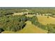 Scenic aerial view captures a beautiful home nestled amongst trees and fields in a tranquil, rural setting at 1973 Elon Ossipee Rd, Elon, NC 27244