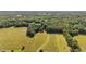 Panoramic aerial shot reveals a home surrounded by lush trees and open fields for secluded country living at 1973 Elon Ossipee Rd, Elon, NC 27244