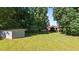 Expansive backyard featuring a lush lawn, mature trees, and an outbuilding perfect for storage or hobbies at 1973 Elon Ossipee Rd, Elon, NC 27244