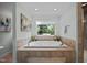 Relaxing bathroom features a large soaking tub, tile surround, and natural light from the window at 1973 Elon Ossipee Rd, Elon, NC 27244