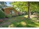Brick home surrounded by mature trees and a lush green lawn, showcasing the landscaped yard at 1973 Elon Ossipee Rd, Elon, NC 27244