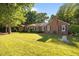Charming brick home featuring a lush green lawn and mature trees on a sunny day at 1973 Elon Ossipee Rd, Elon, NC 27244