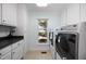 Bright laundry room with white cabinetry, black countertops, and modern washer and dryer at 1973 Elon Ossipee Rd, Elon, NC 27244